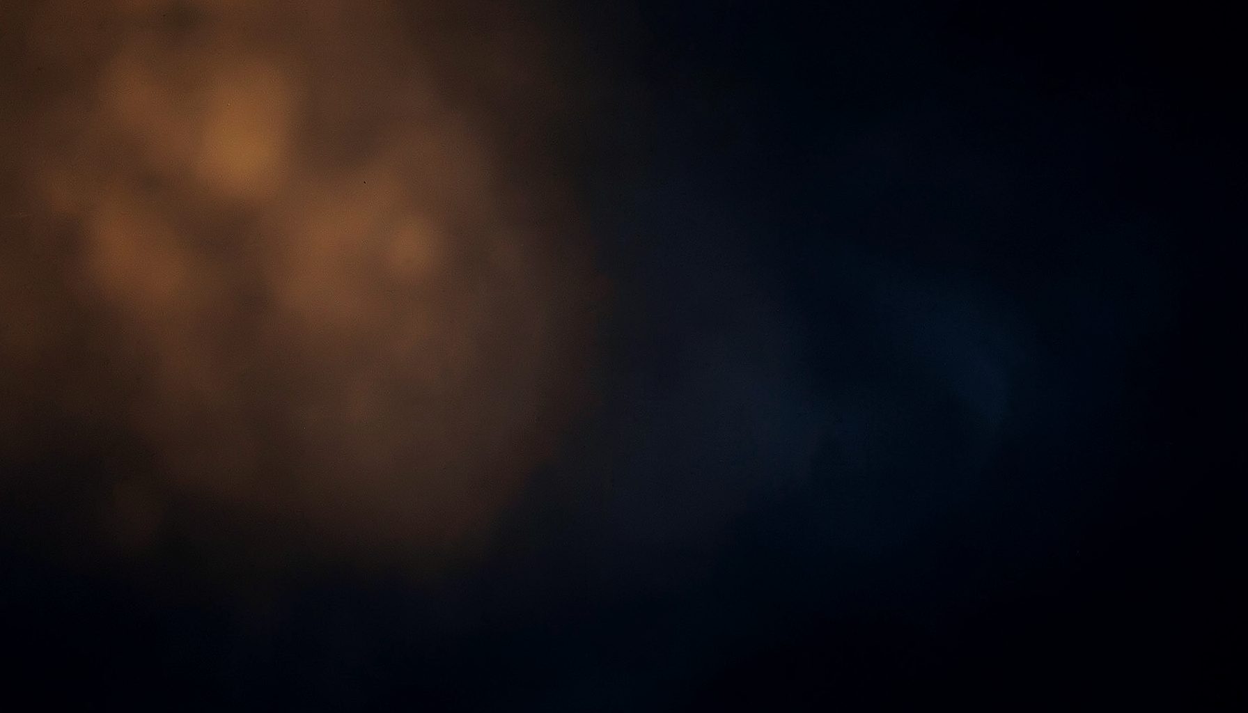 Dark atmospheric background with soft warm amber and deep navy tones, suggesting a quiet music-listening mood