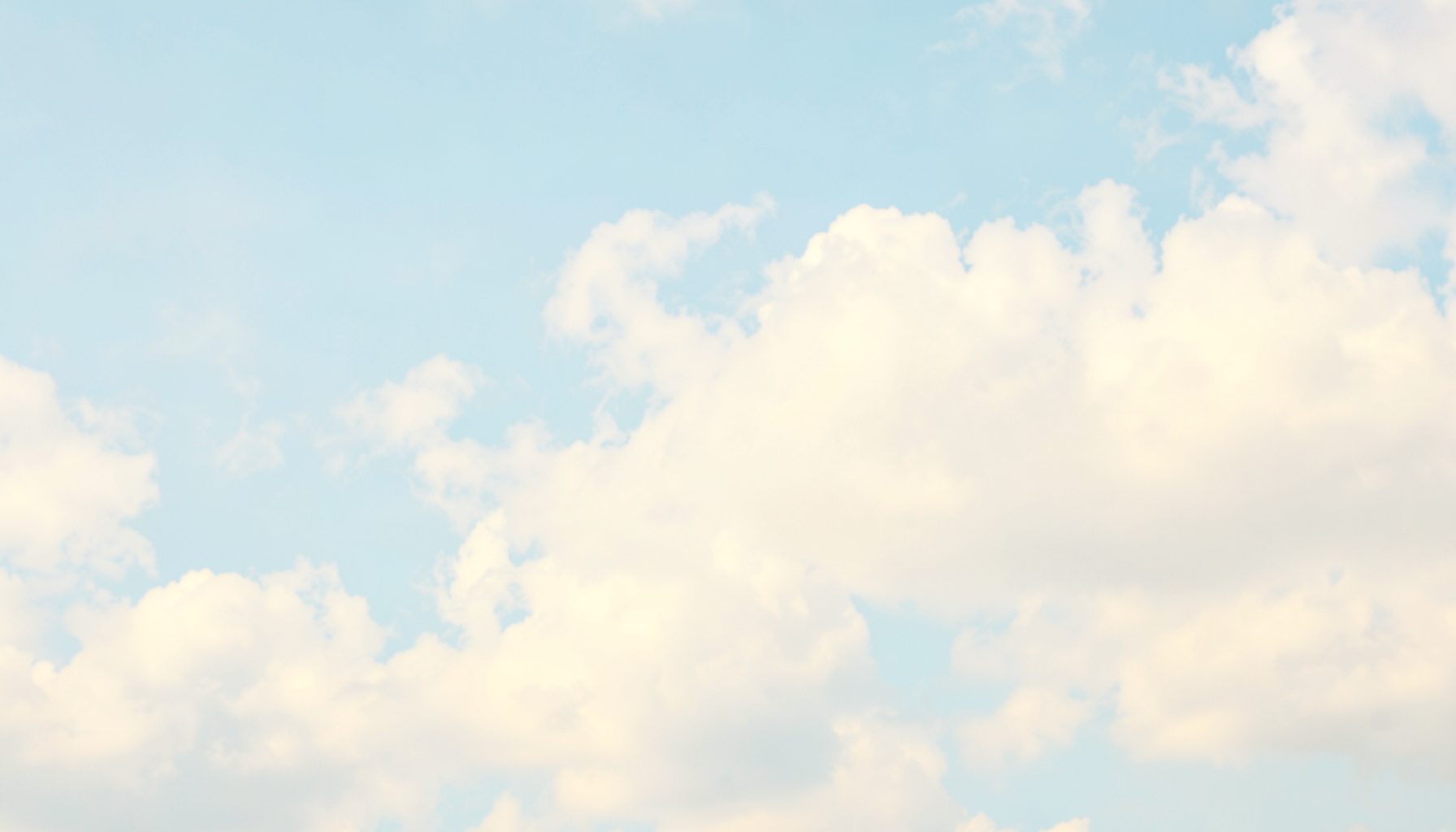 Soft pastel sky with fluffy white clouds in pale blue and cream tones, evoking a gentle dreamlike atmosphere